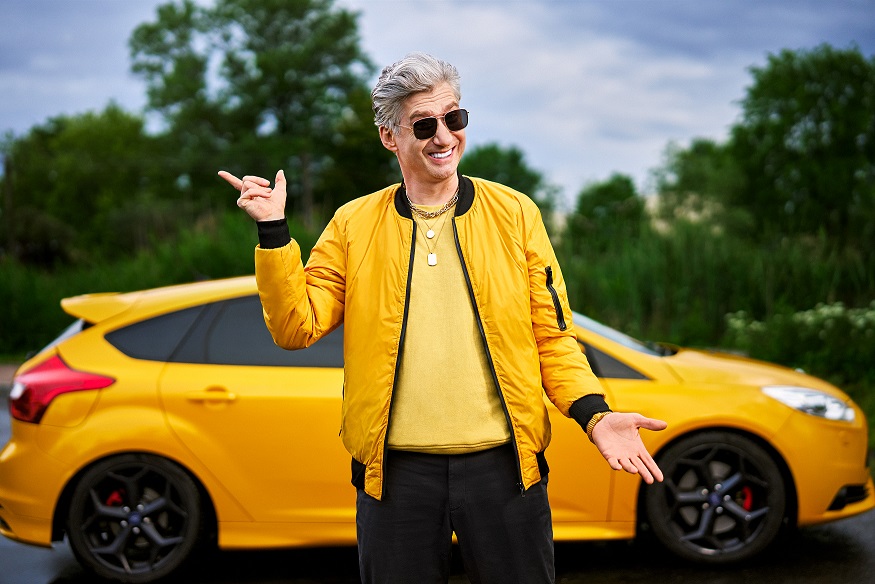 Informacja o 15% zniżki za zakup online na tle zdjęcie przedstawia uśmiechniętego mężczyznę stojącego na tle samochodu. Osoba na zdjęciu dłonią wskazuje na baner z formularzem. 